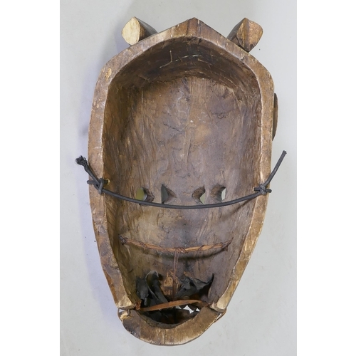 44 - An African tribal carved wood horned mask with hinged jaw, 50cm long, AF minor loss and break