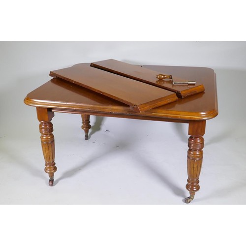 1141 - A Victorian mahogany wind out dining table with two extra leaves, raised on turned and fluted suppor... 