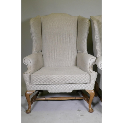 1148 - A good pair of Georgian style high back wing armchairs with wide seats, raised on walnut cabriole su... 