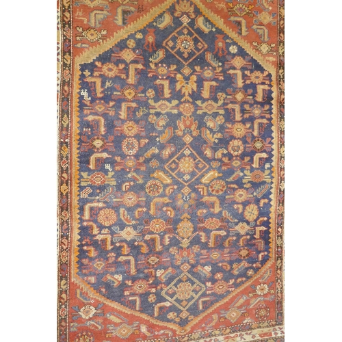 1018 - An antique Persian hand woven wool carpet, with medallion design on a red and blue field with ivory ... 