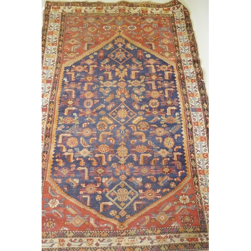 1018 - An antique Persian hand woven wool carpet, with medallion design on a red and blue field with ivory ... 