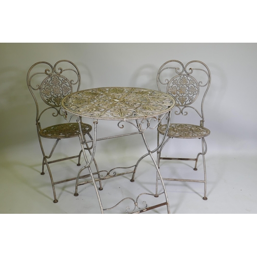 1019 - A painted and distressed metal bistro table and two folding chairs, 69cm diameter