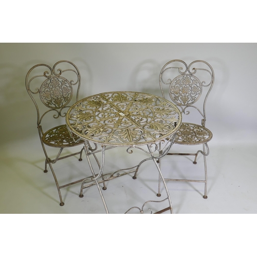 1019 - A painted and distressed metal bistro table and two folding chairs, 69cm diameter