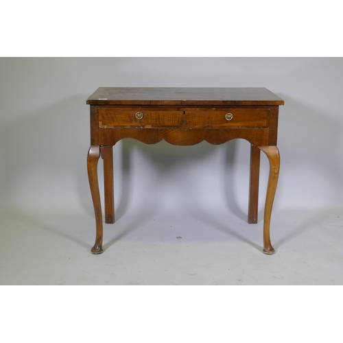 1030 - A Georgian style walnut two drawer writing table, with cross banded top, raised on cabriole supports... 