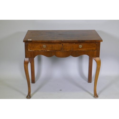 1030 - A Georgian style walnut two drawer writing table, with cross banded top, raised on cabriole supports... 