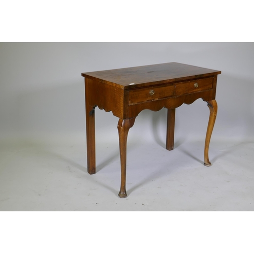 1030 - A Georgian style walnut two drawer writing table, with cross banded top, raised on cabriole supports... 