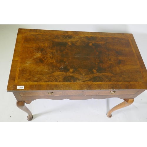 1030 - A Georgian style walnut two drawer writing table, with cross banded top, raised on cabriole supports... 