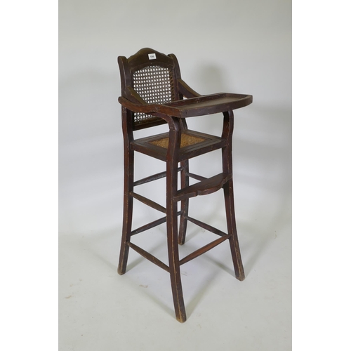 1046 - An oriental hardwood child's highchair with can back and seat, 103cm high