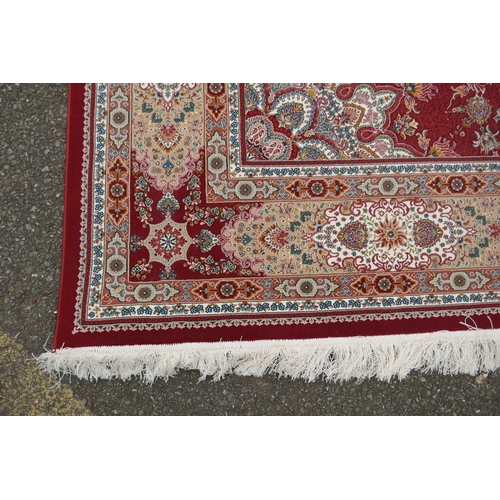 1048 - A fine woven full pile rich red ground Qom carpet, with floral medallion design and floral borders, ... 