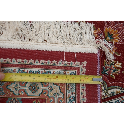 1048 - A fine woven full pile rich red ground Qom carpet, with floral medallion design and floral borders, ... 