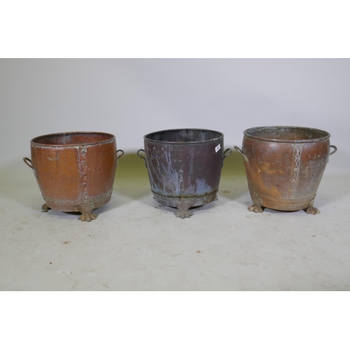 1069 - A near pair of copper planters/jardinieres of rivetted construction, raised on paw feet, and another... 