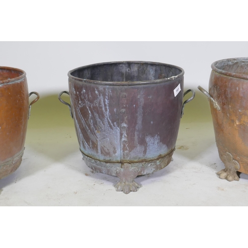 1069 - A near pair of copper planters/jardinieres of rivetted construction, raised on paw feet, and another... 