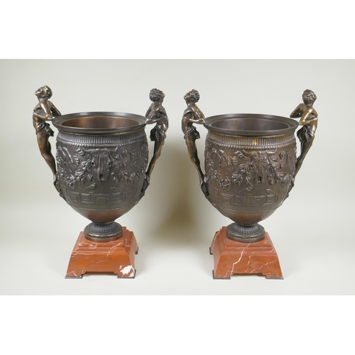 107 - A pair of Grand Tour style bronze urns on red marbled bases, with male figural twin handles, 41cm hi... 