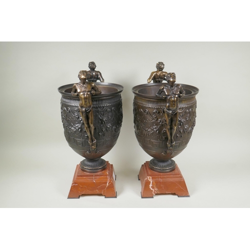 107 - A pair of Grand Tour style bronze urns on red marbled bases, with male figural twin handles, 41cm hi... 