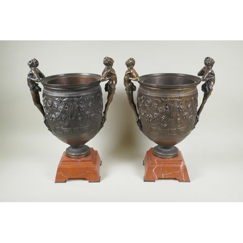 107 - A pair of Grand Tour style bronze urns on red marbled bases, with male figural twin handles, 41cm hi... 