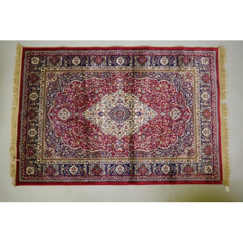 1077 - A red ground Kashmir rug with traditional floral medallion design and blue borders, 170 x 120cm