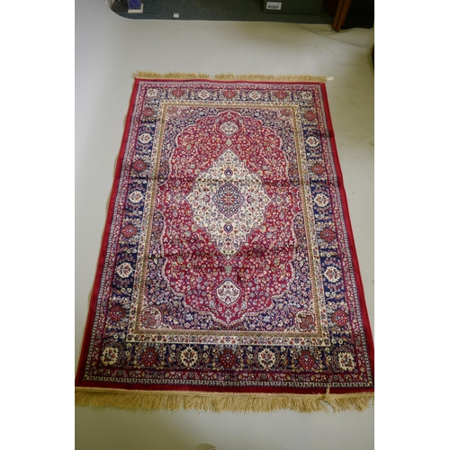 1077 - A red ground Kashmir rug with traditional floral medallion design and blue borders, 170 x 120cm