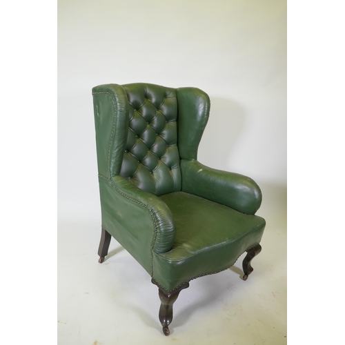 1084 - An early C20th button back leather wing armchair, raised on cabriole supports