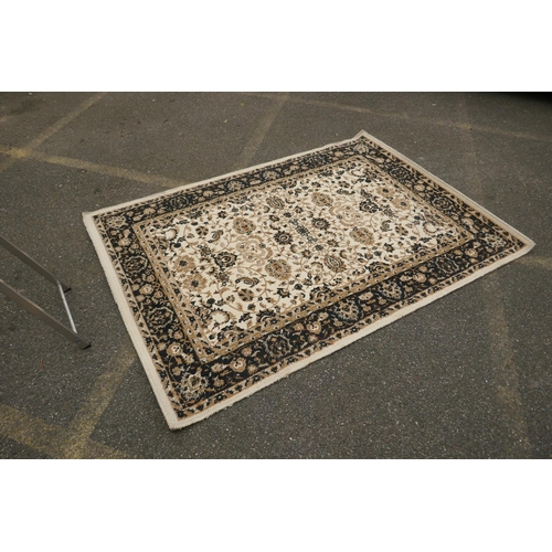 1086 - A Belgian cream ground rug with Oriental allover floral design and black borders, 150 x 212cm