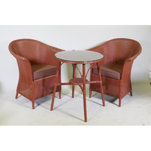 1130 - A Lloyd Loom occasional table with glass top and two armchairs, 60cm diameter