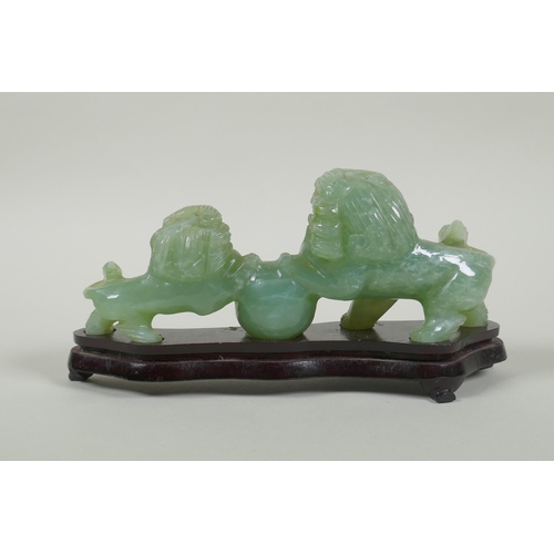 115 - A Chinese celadon jade carving of twin fo-dogs, on a lacquered wood stand, 21cm long