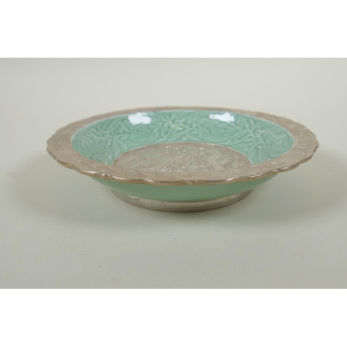 123 - A Chinese celadon and silver glazed porcelain dish with raised dragon and lotus flower decoration, Q... 