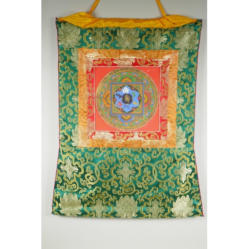 138 - A Tibetan hand painted Mandala, in an embroidered silk mount, 53 x 67cm