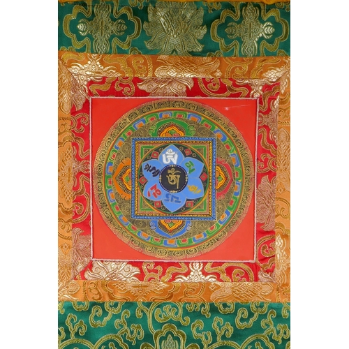 138 - A Tibetan hand painted Mandala, in an embroidered silk mount, 53 x 67cm