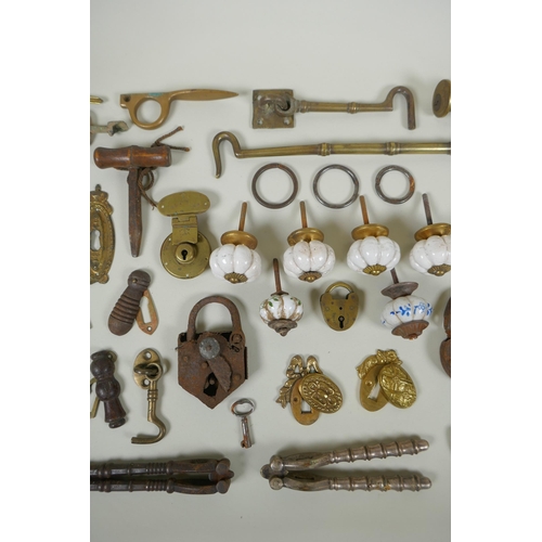 141 - A collection of antique bronze and brass door furniture, porcelain drawer handles, locks and keys