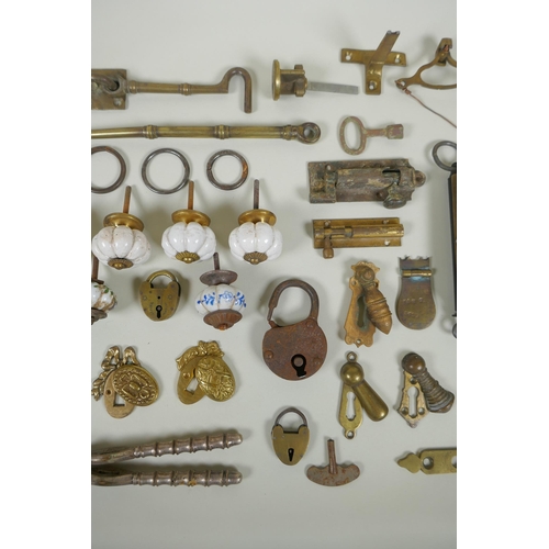 141 - A collection of antique bronze and brass door furniture, porcelain drawer handles, locks and keys