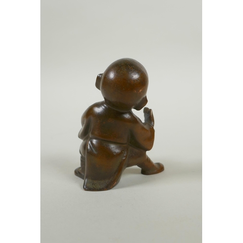 142 - An Oriental bronze figure of a child practising martial arts, 9cm high