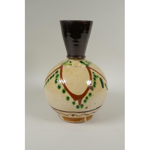 179 - An antique Islamic earthenware vase with cream glazed body and treacle glazed neck, 25cm high