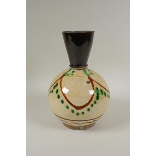 179 - An antique Islamic earthenware vase with cream glazed body and treacle glazed neck, 25cm high