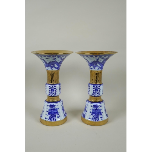 188 - A pair of Chinese blue and white gu shaped vases with banded gilt highlights, and decorated with pho... 