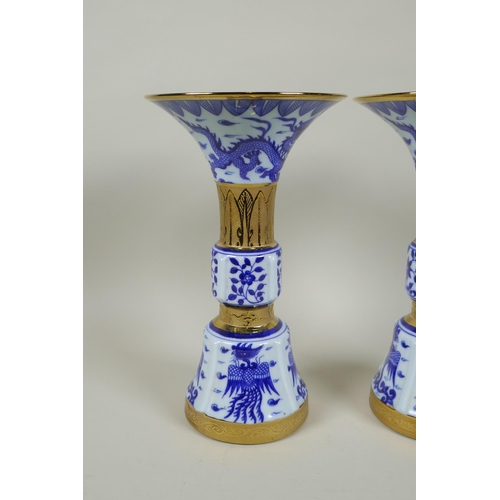 188 - A pair of Chinese blue and white gu shaped vases with banded gilt highlights, and decorated with pho... 