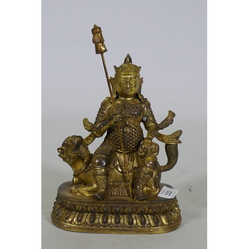 222 - A Chinese gilt bronze figure of a deity seated on a dragon, 26cm high