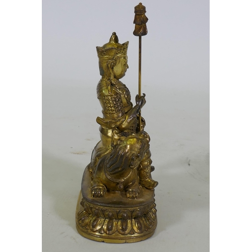 222 - A Chinese gilt bronze figure of a deity seated on a dragon, 26cm high