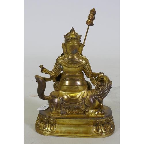 222 - A Chinese gilt bronze figure of a deity seated on a dragon, 26cm high