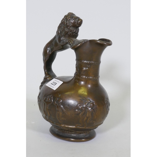 229 - An antique cast bronze pitcher, with raised Bacchanalian decoration and lion handle, 23cm high