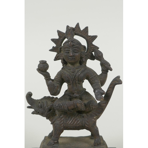 24 - An antique Indian bronze figure of Durga riding a mythical creature, 12cm high