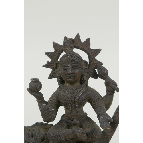 24 - An antique Indian bronze figure of Durga riding a mythical creature, 12cm high