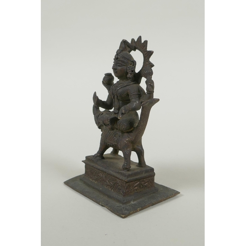 24 - An antique Indian bronze figure of Durga riding a mythical creature, 12cm high