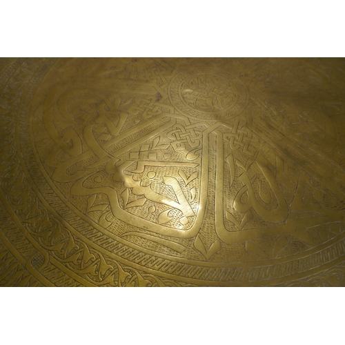 57 - A large Indo/Persian copper tray, 64cm wide, and a brass tray with Islamic calligraphy decoration