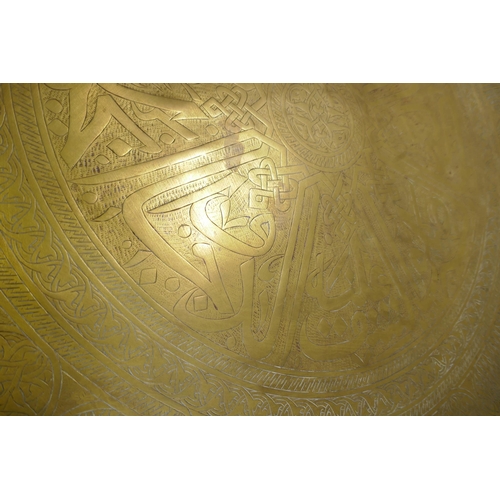 57 - A large Indo/Persian copper tray, 64cm wide, and a brass tray with Islamic calligraphy decoration