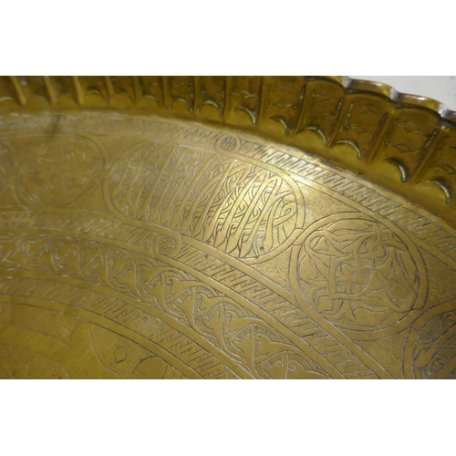 57 - A large Indo/Persian copper tray, 64cm wide, and a brass tray with Islamic calligraphy decoration