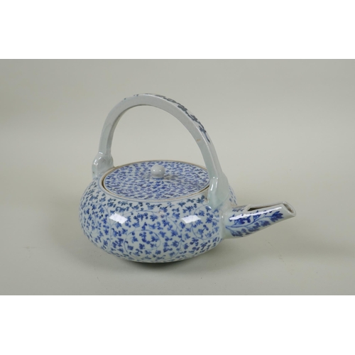 80 - An early C20th Japanese blue and white porcelain tea pot of squat form, with all over scrolling vine... 