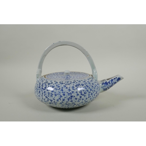 80 - An early C20th Japanese blue and white porcelain tea pot of squat form, with all over scrolling vine... 