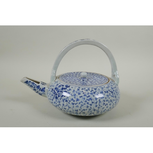 80 - An early C20th Japanese blue and white porcelain tea pot of squat form, with all over scrolling vine... 