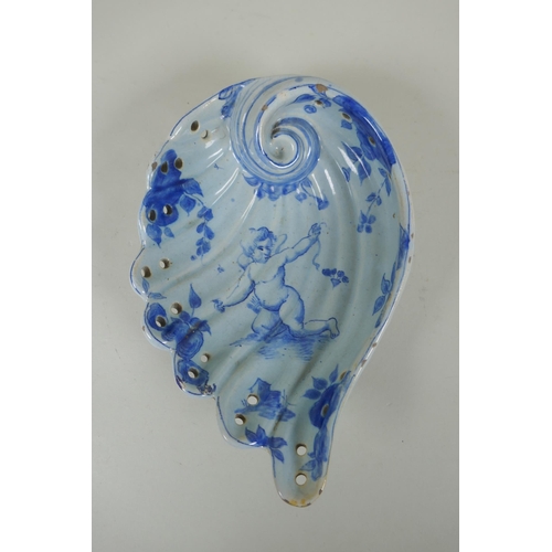 99 - An antique Cantagalli faience blue and white shell shaped dish with putto decoration, 21 x 14cm