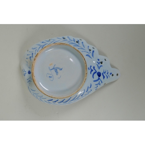 99 - An antique Cantagalli faience blue and white shell shaped dish with putto decoration, 21 x 14cm